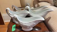 Group of five white ironstone gravy boats on table