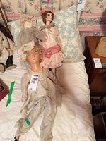 Three dolls lying on bed showing overall variety and condition