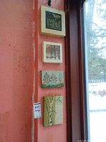 Four small landscape paintings mounted vertically on wall