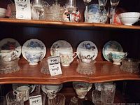 Shelf with multiple teacup/saucer pairs and glass dishes