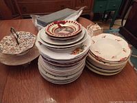 Stacks of assorted plates, bowls, cake stand and linen on table