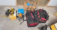Group shot: boxed brad nailer, router, tool bags, router bit case, paper bag, cords
