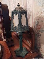 Full view of lamp showing base, stem, ornate shade and slag glass panels