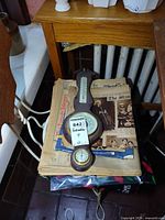 Barometer resting on stack of newspapers