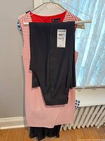 Carré Noir red and white sheath dress with black pants draped over hanger