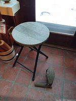 Folding stool next to shoe last on tiled floor