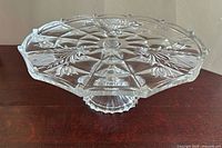 Full view of crystal pedestal cake stand on dark surface