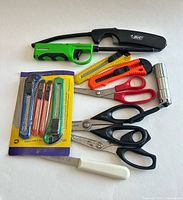 Overview of lot showing utility knives, scissors, lighters, paring knife and flashlight