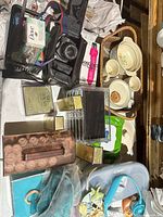 Top-down view showing Canon camera with case, acrylic drawers, perfume boxes, ceramic dishware, Conair foot spa