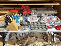 Overall view of table with knife block, mixing bowls, muffin pan, immersion blender, plastic containers