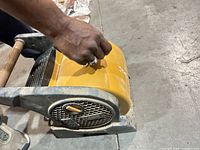 Close view of Lasko air mover front grille, yellow housing, user hand on control knob