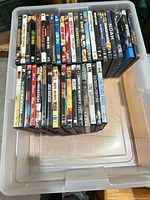 Top view of plastic bin containing roughly forty DVD cases, spines visible.