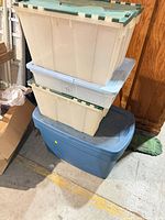 Three stacked plastic storage totes showing lids and colors