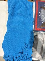 Blue knitted throw with tassel ends beside partial eagle pillow