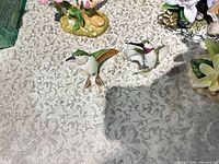 Two individual hummingbird figurines on patterned surface