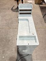 Top angled view of entire manicure table showing recessed work area, sink cut-out, shelves and power outlet