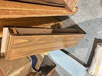 Top view of one cabinet drawer showing wood grain veneer front and particleboard construction