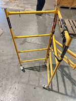 Overall view of yellow MetalTech steel rolling scaffold frame with four casters