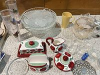 overview of ceramic apple pieces, glass stands, plastic tumblers, pitcher and small glasses