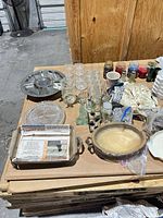 Overview of mixed glassware, trays, figurine, candles, linens on tabletop