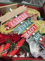 Interior of organizer showing wood word signs, fabric poinsettia, gold mesh, greenery