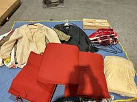 Overview of jackets, red cushions, beige pad, plaid throw, hangers, box of vacuum attachments on floor