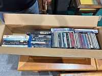 Open cardboard box with DVDs, Blu-rays, CDs and VHS visible