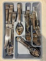Stainless flatware set in grey plastic tray