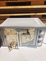 Front view of Oster air fryer oven with doors and control knobs visible