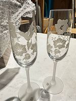 Both flutes upright showing etched design and frosted stems