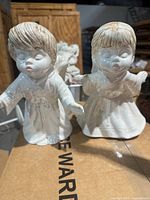 Front view of both porcelain angel figurines standing on box