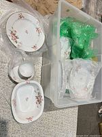 Open storage tote showing oval platter, teacup, saucer, oval serving bowl and additional wrapped pieces