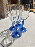 Four clear wine glasses standing, blue stems visible