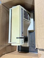 Top and side view of beige computerized sewing machine inside box