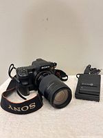 Front view of Sony Alpha A700 with Minolta zoom lens, neck strap and charger visible