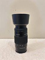 Front view showing lens with hood attached and focal length/aperture markings