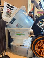 Stack of clear plastic storage containers beside exercise bike