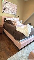 Full view of pink faux leather bed frame with bedding