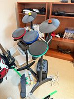 Wide view of Rock Band drum kit, guitars, Wii console and games on shelves