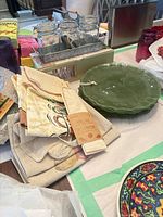 Stack of green plates, Mason jars in caddy, folded linens