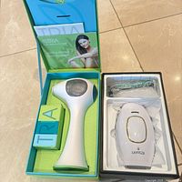 Open TRIA and Lanveza boxes showing both hair-removal devices and accessories