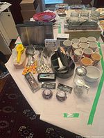 Overview of lot showing cutting board stand, utensils, thermometers, baking cups, knife holder, sugar/creamer set and mason jars