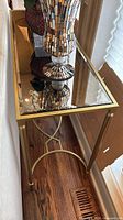 Angled view of entire console table behind sofa showing gold frame and glass top