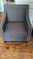 Front view of gray linen armchair showing nailhead trim and seat cushion