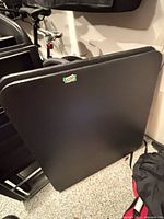 Both black folding tables leaned against wall showing laminate tops