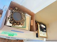 Box with ornate oval frame and additional frames; wall clock beside box