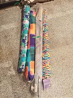 Four rolled beach umbrellas with patterned sleeves on floor