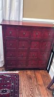 Front view showing burgundy cabinet with multiple drawer fronts