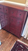 Front view of burgundy wood cabinet showing multiple square drawer fronts