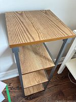 Front angled view showing full shelving unit with four wooden shelves and metal frame